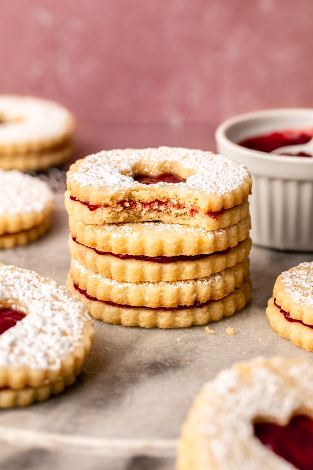 three linzer cookies stacked on top of each other with the cookie on top bitten to show the inner texture of the cookie