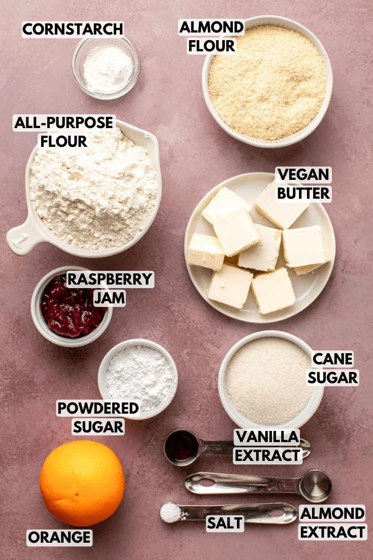 ingredients for vegan linzer cookies served in various white bowls on a marble kitchen countertop