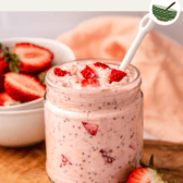 jar of strawberry overnight oats on wooden serving board with white spoon