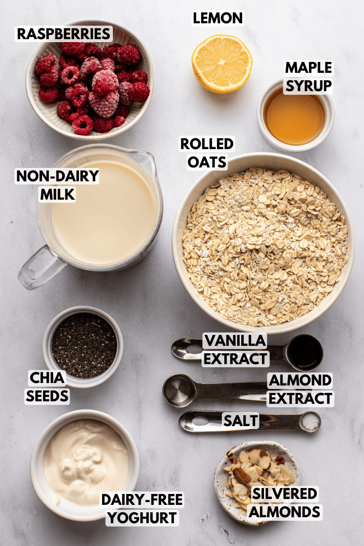 ingredients for raspberry overnight oats laid out on a marble kitchen countertop