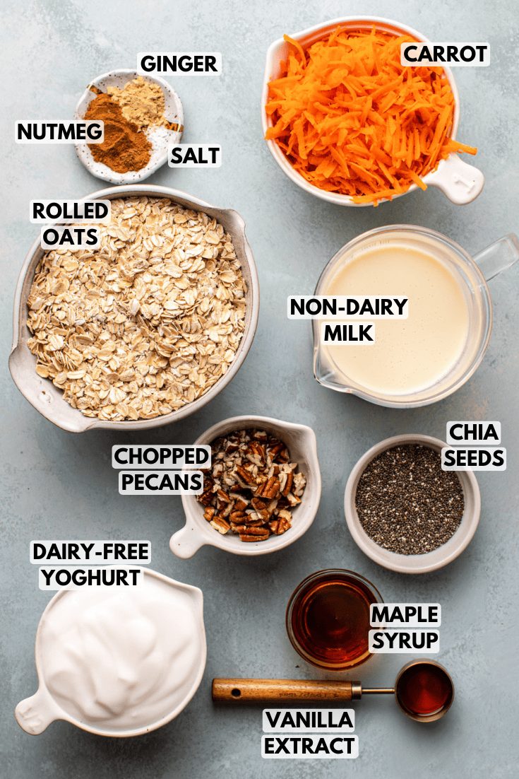 ingredients for carrot cake overnight oats served in various sizes of white bowls placed on a light blue countertop