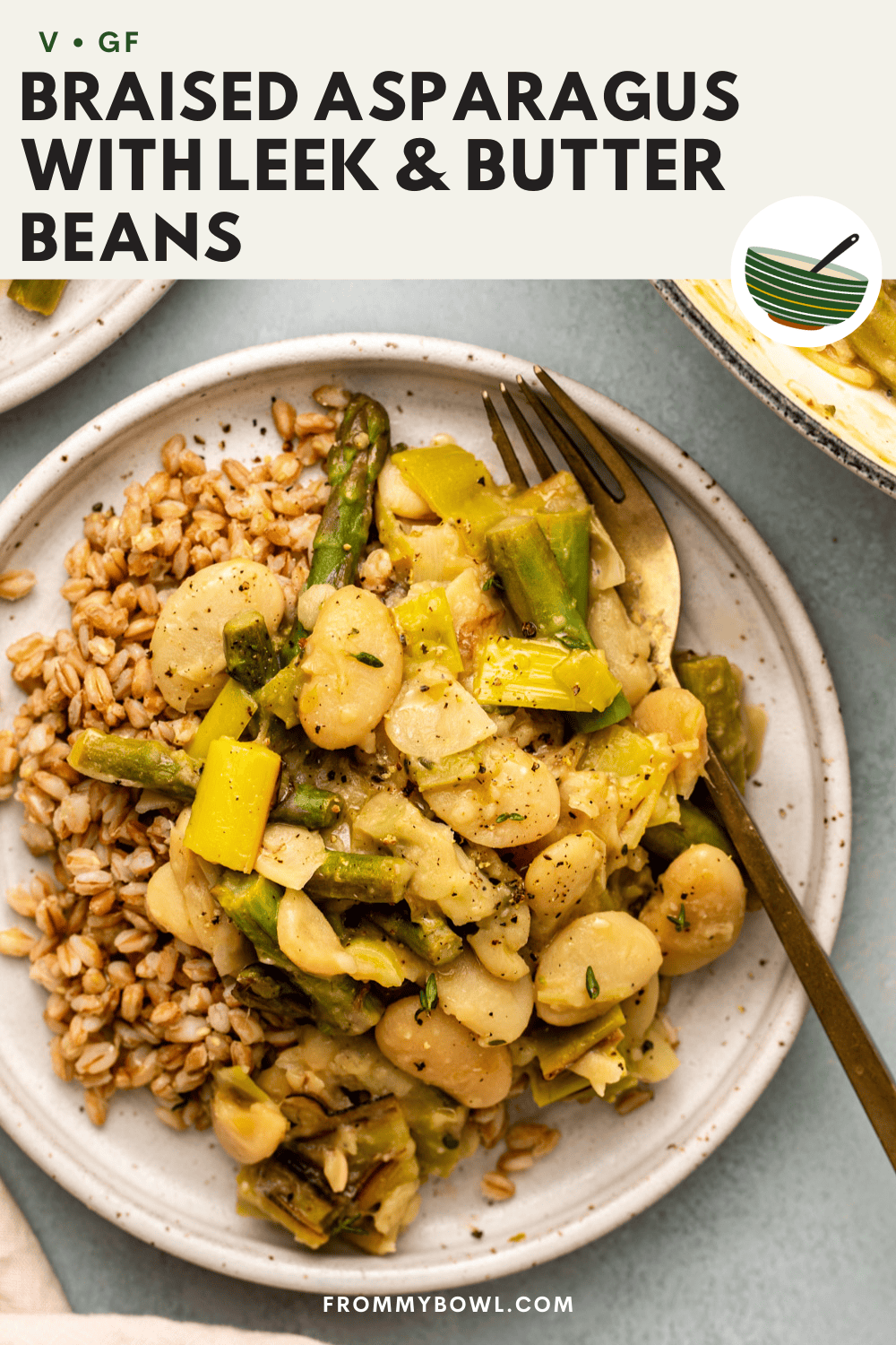 braised asparagus with leeks and butter beans served over cooked grains on a white plate with a fork ready to dig in