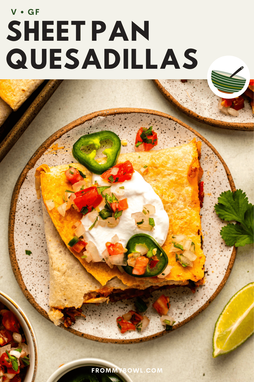 a slice of sheet pan quesadillas served in a plate topped with salsa, sour cream and jalapeno slices