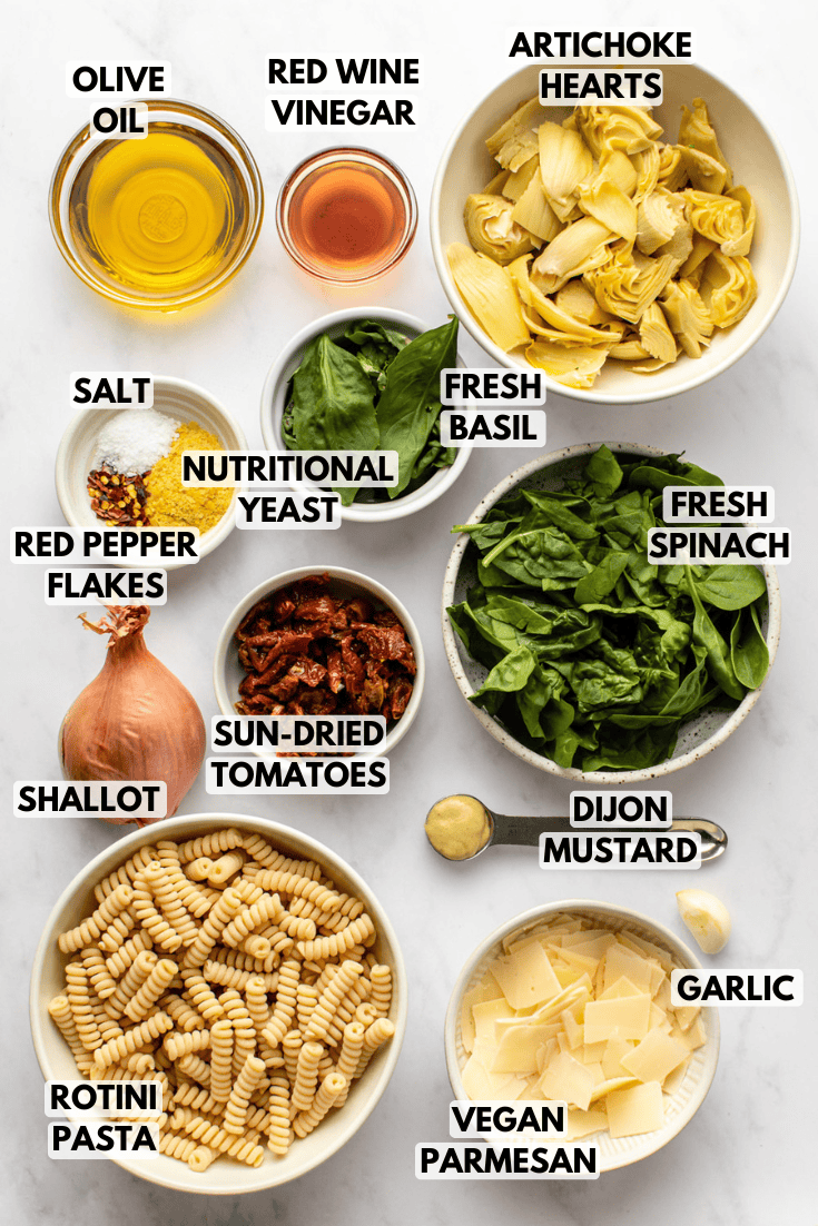 ingredients for spinach basil artichoke pasta laid out on a marble kitchen countertop