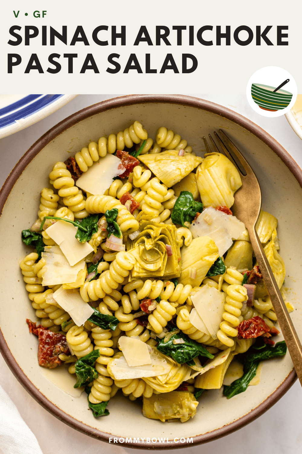 spinach artichoke pasta served in a bowl with a metal spoon place on it