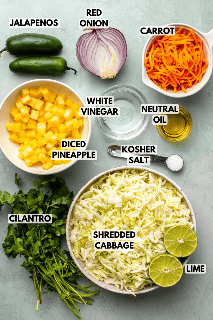 ingredients for pineapple coleslaw served in various bowls on a light green kitchen countertop