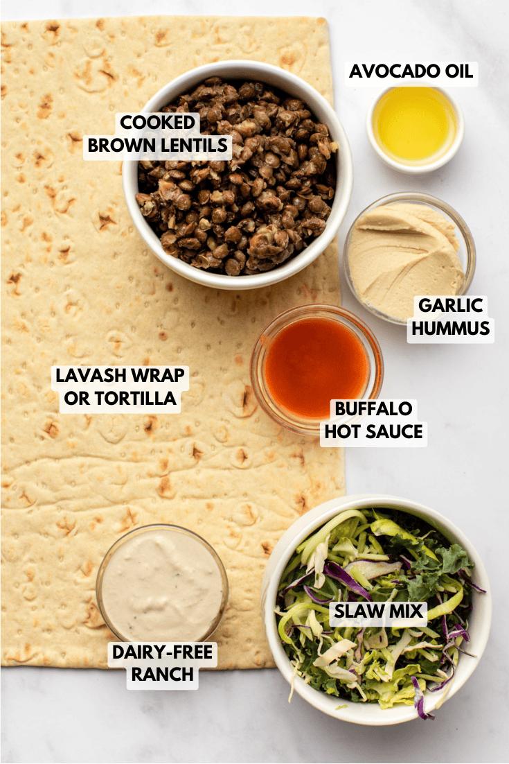 wrap ingredients arranged on a tortilla laid out on a kitchen counter, prepared for assembling a crispy lentil buffalo wrap.