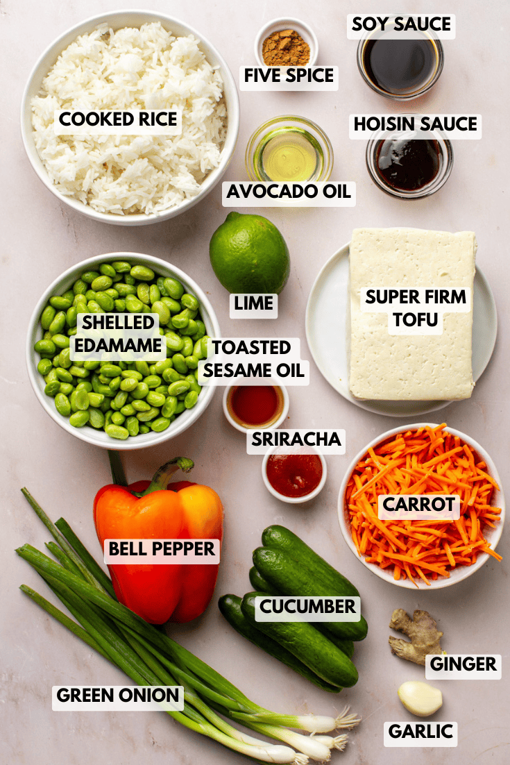 ingredients for crispy rice salad arranged on a countertop, including rice, tofu, edamame, fresh vegetables, and Asian-inspired sauces.
