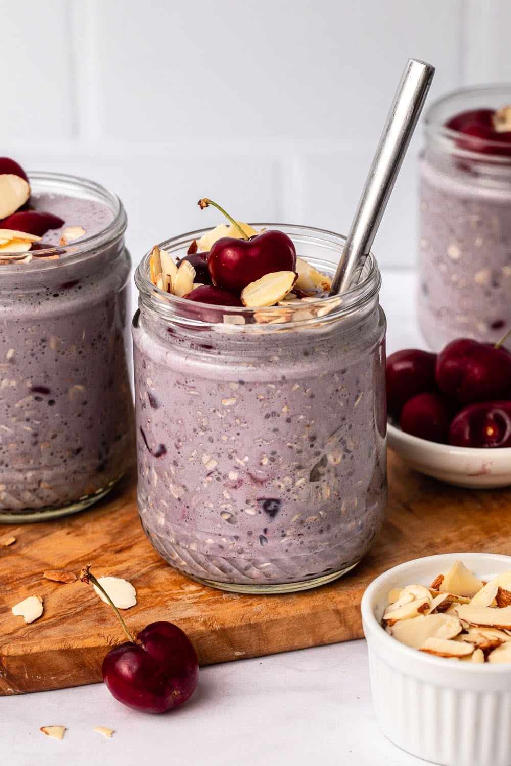 cherry overnight oats in a glass jar, topped with fresh cherries and sliced almonds.