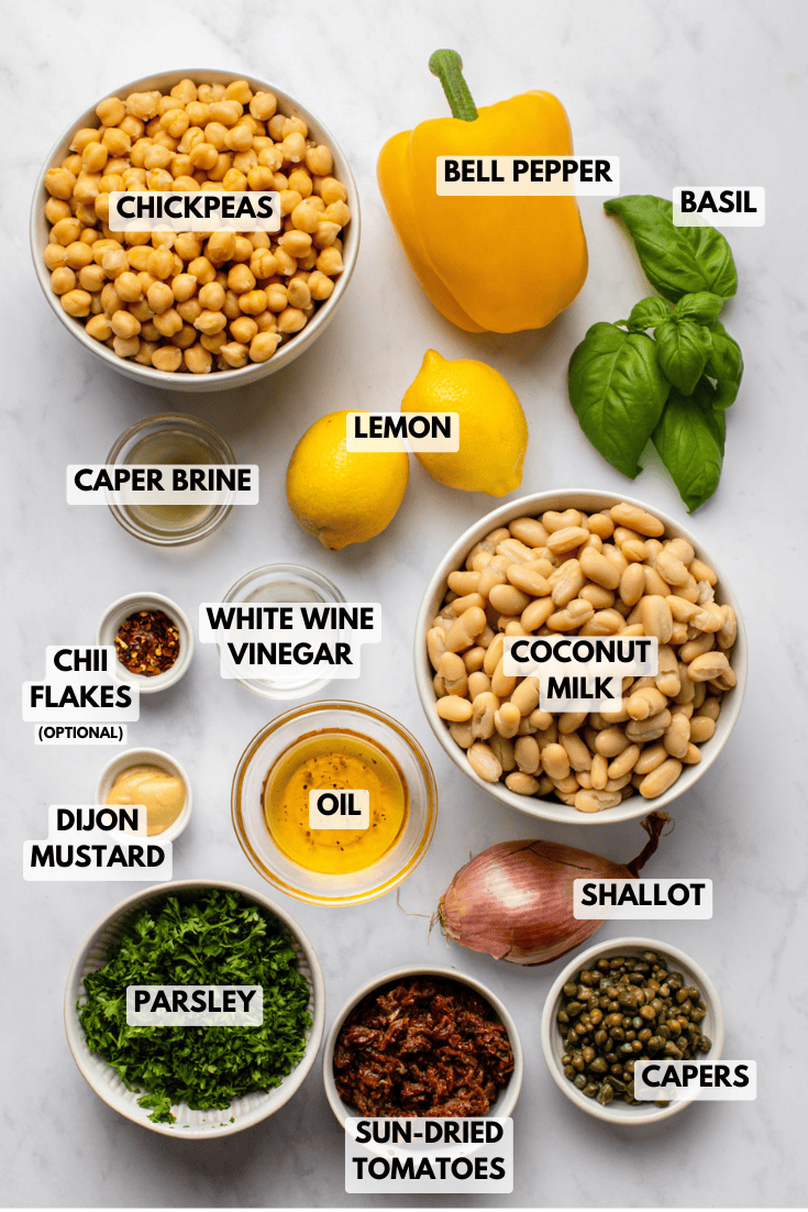 ingredients for a lemon caper bean salad, including white beans, chickpeas, lemon, parsley, basil, shallot, capers, sun-dried tomatoes, yellow bell pepper, olive oil, dijon mustard, and vinegar.
