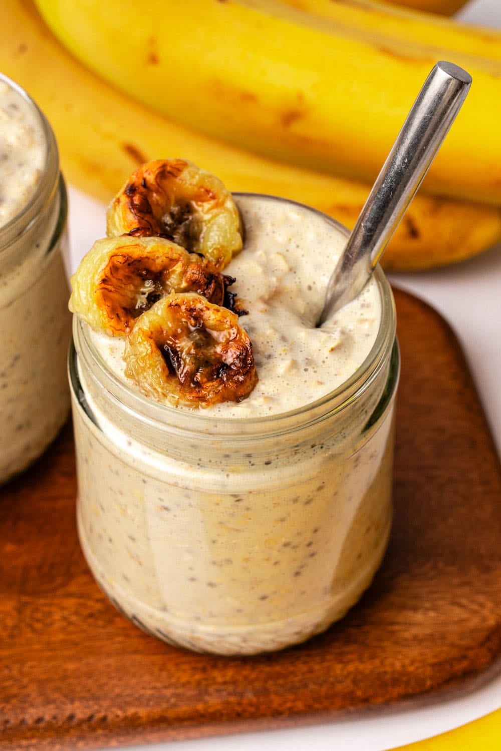 caramelized banana overnight oats in a glass jar topped with roasted banana slices.